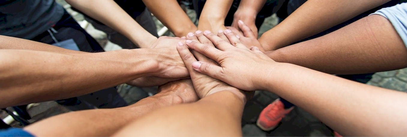 Das Bild zeigt die Arme mehrerer Menschen, die Ihre Hände alle übereinanderlegen, als Ausdruck dafür, dass sie zusammenhalten